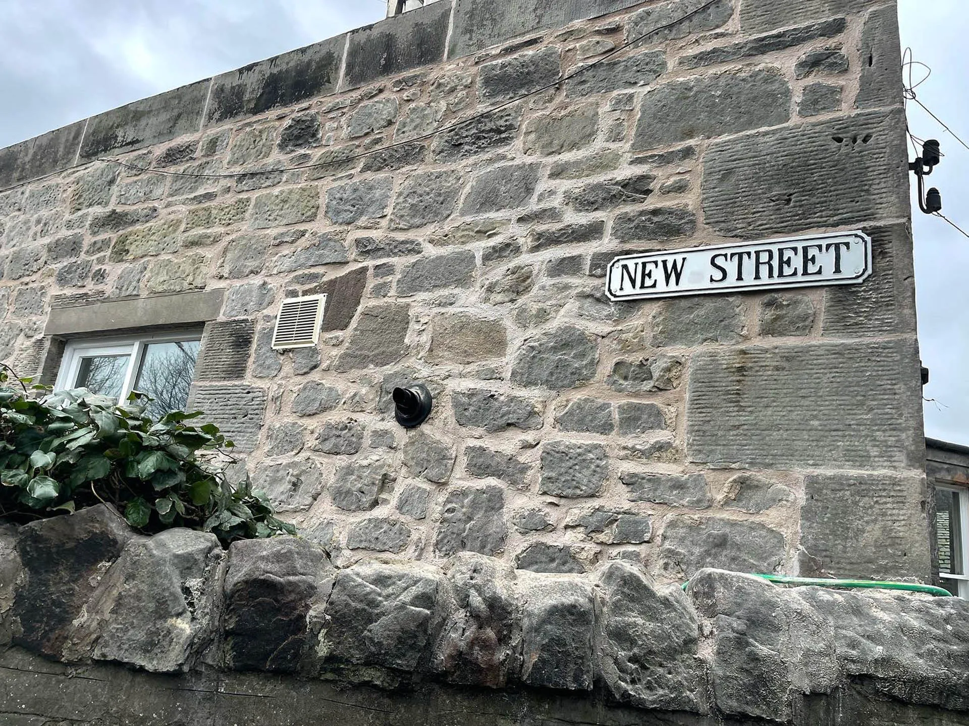 Rebuilt rubble stone wall beneath a New Street sign