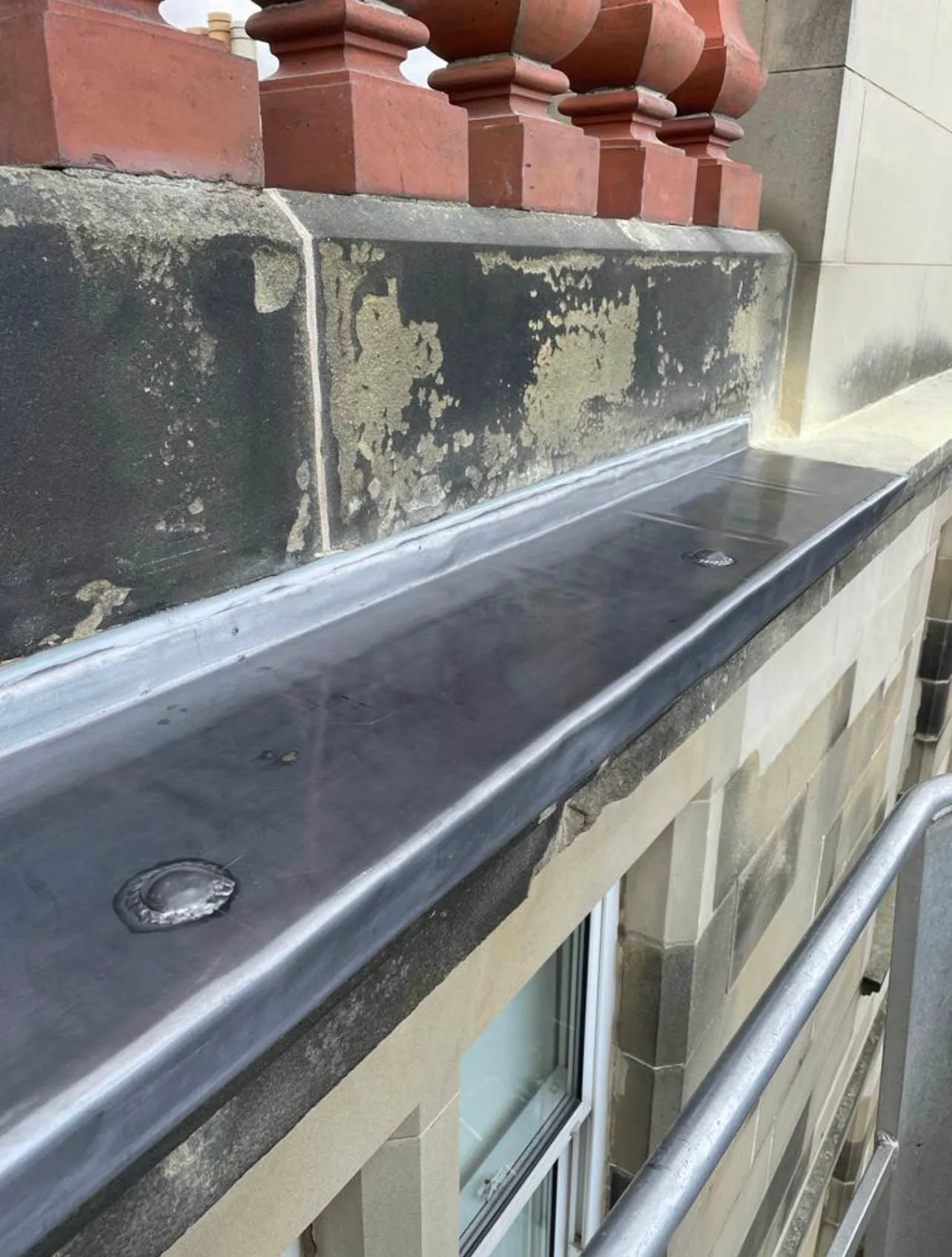 Parapet gutter newly lined with lead, red chimney pots above