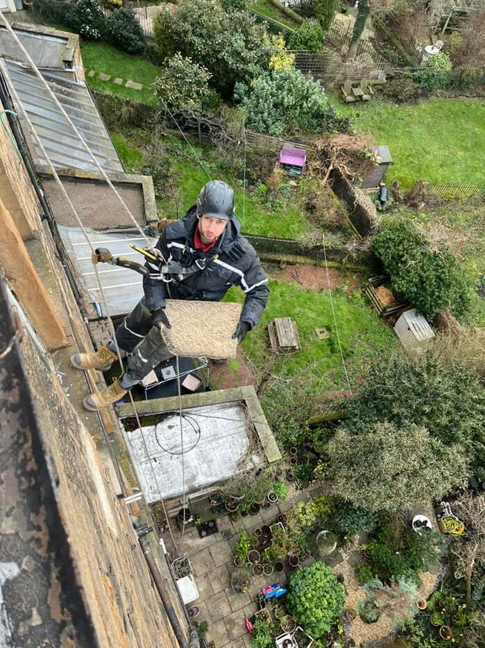 Rope access technician abseiling down the rear of a building to inspect it