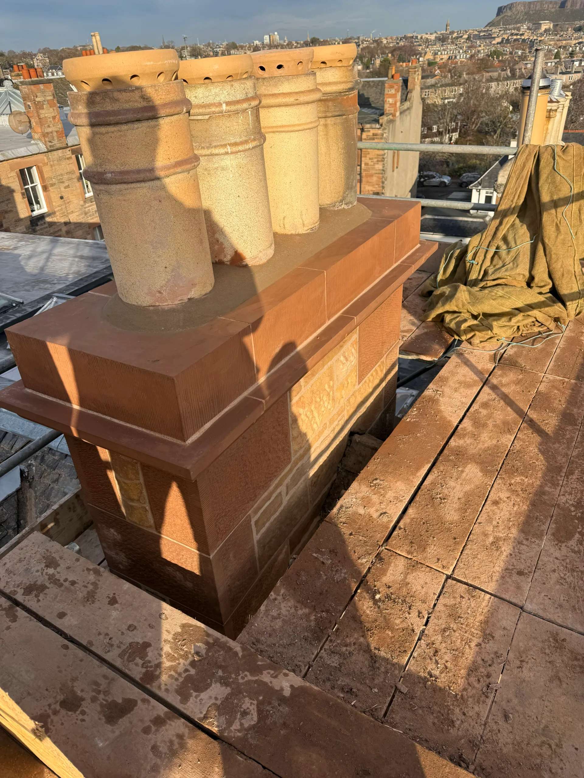 Rebuilt sandstone chimney head with a row of clay pots