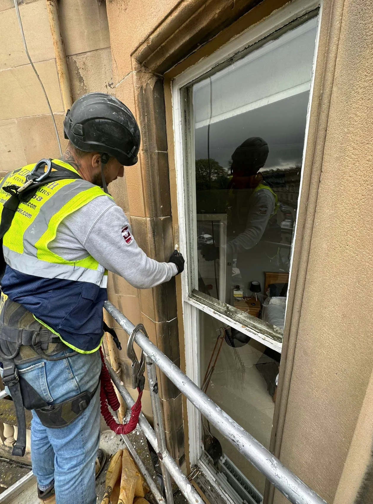 Operative working at a window from a cherry picker platform