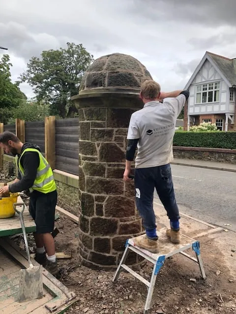 Stonemasons rebuilding a round stone gate pillar in lime mortar