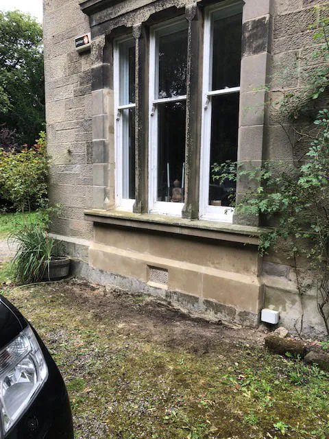 Repaired sandstone bay window surround on a stone house