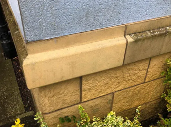Corner of an ashlar stone wall, part cleaned to show the contrast with the soiled stone