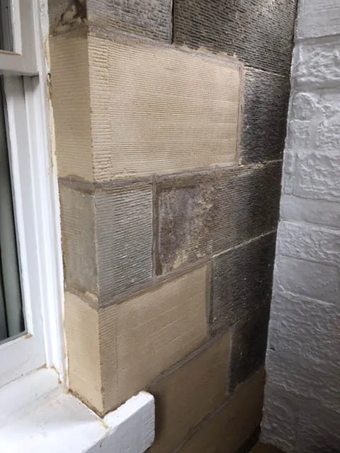 Sandstone wall corner with newly indented replacement blocks beside the older stone