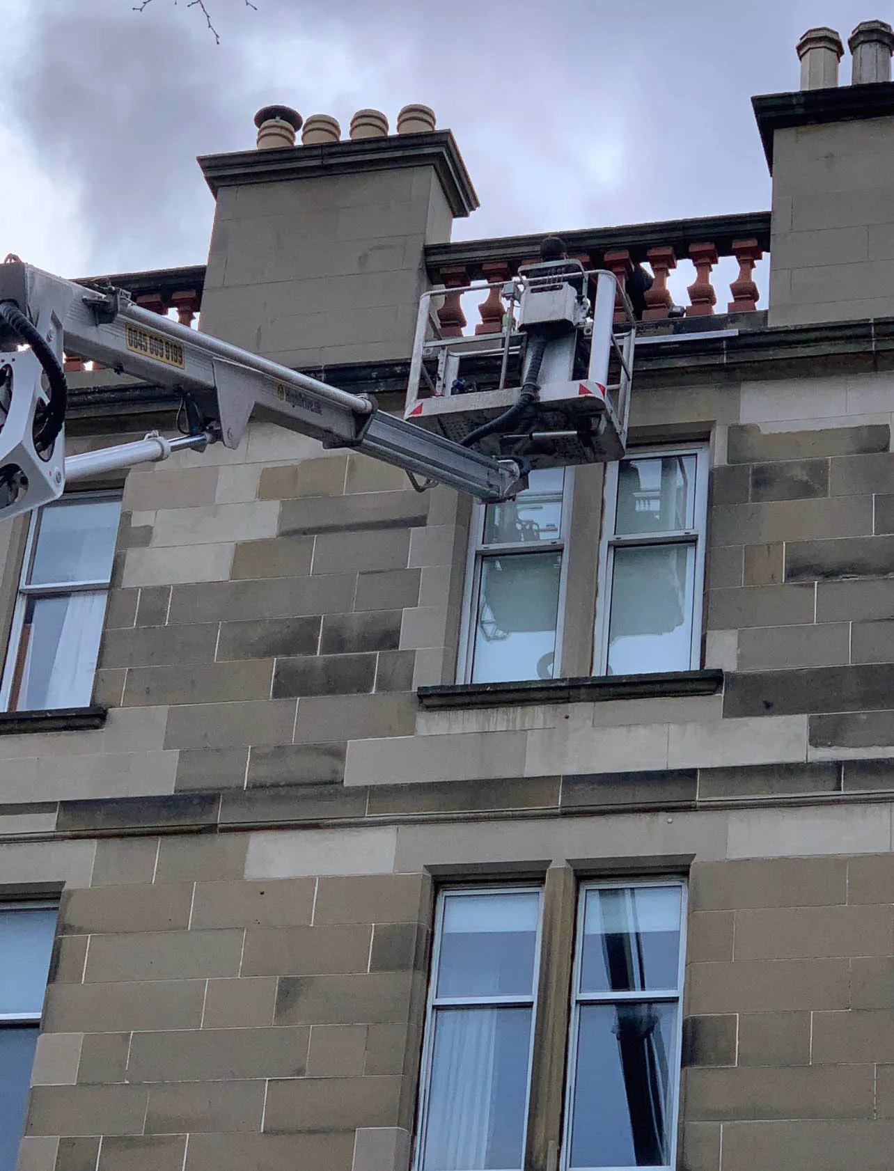 Cherry picker reaching the roof of a tenement to access the chimneys