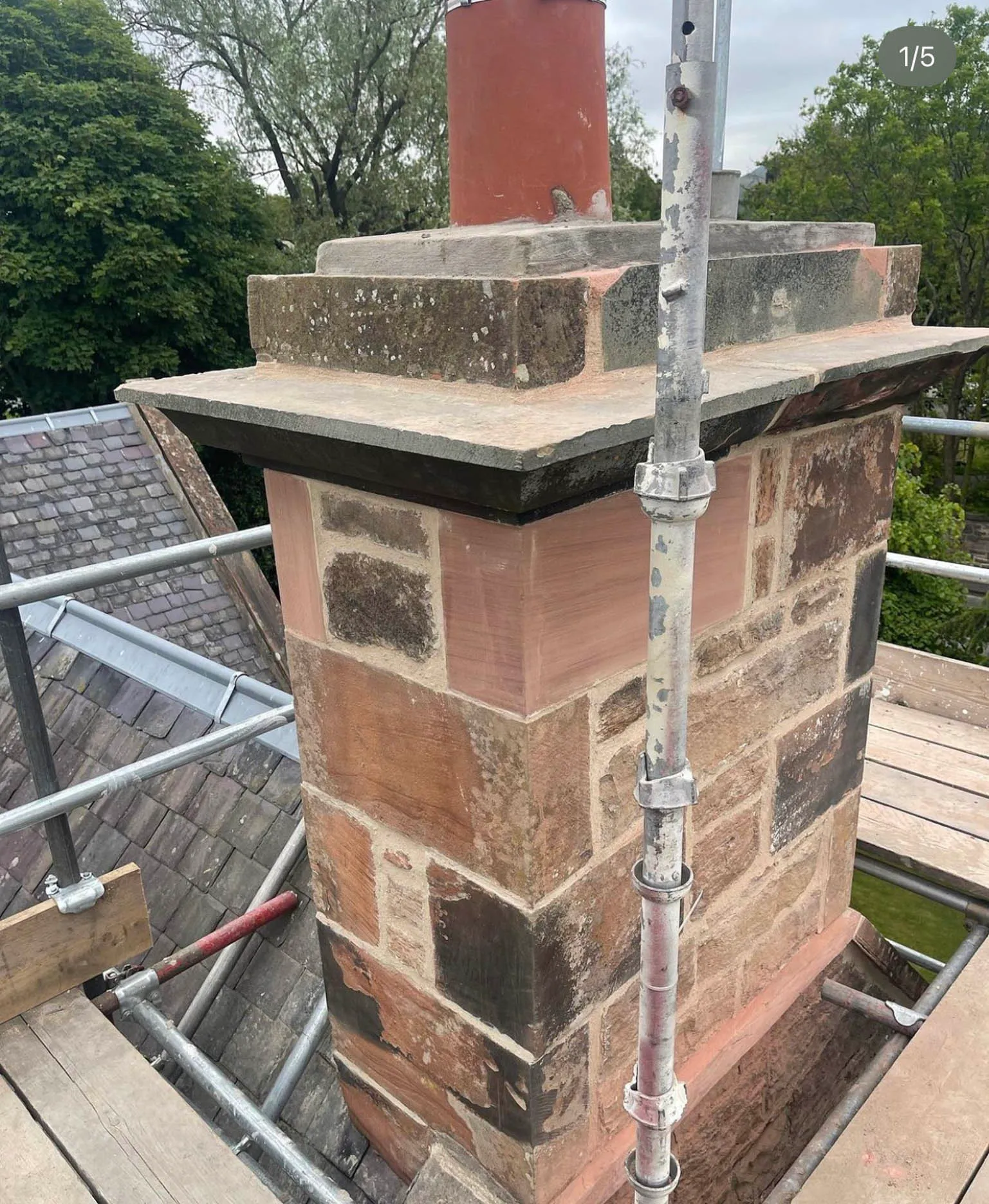 Red sandstone chimney stack being rebuilt, with scaffolding around it