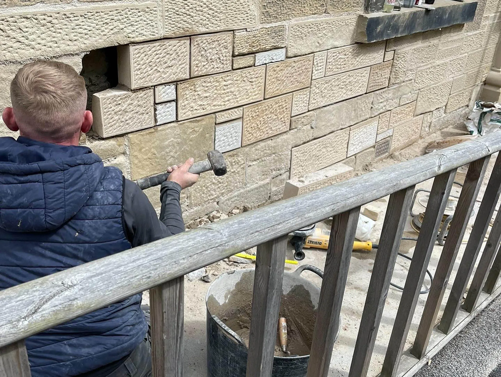 Stonemason repairing an ashlar wall from a scaffold