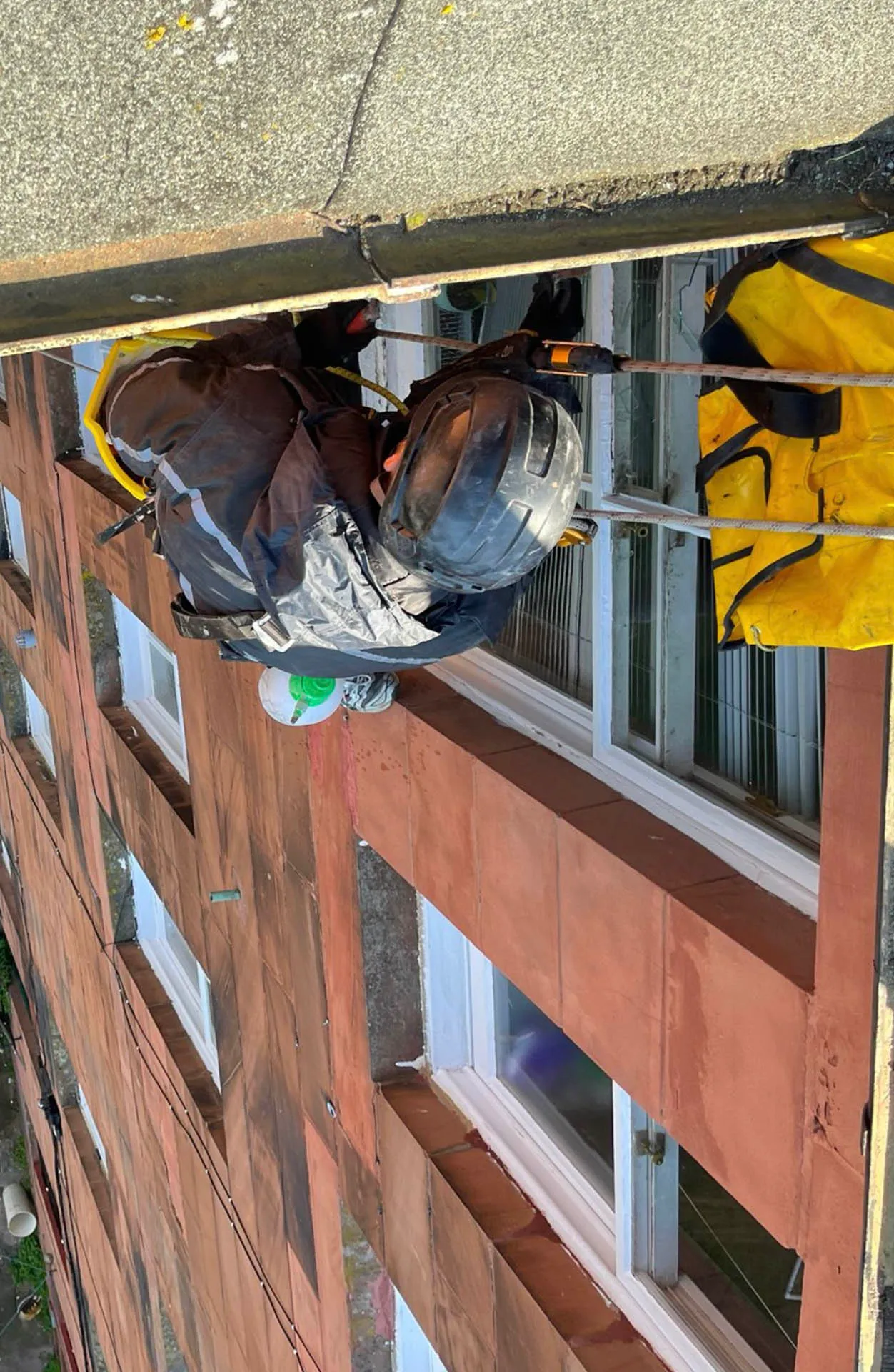 Rope access operative’s seat and equipment rigged beside a window