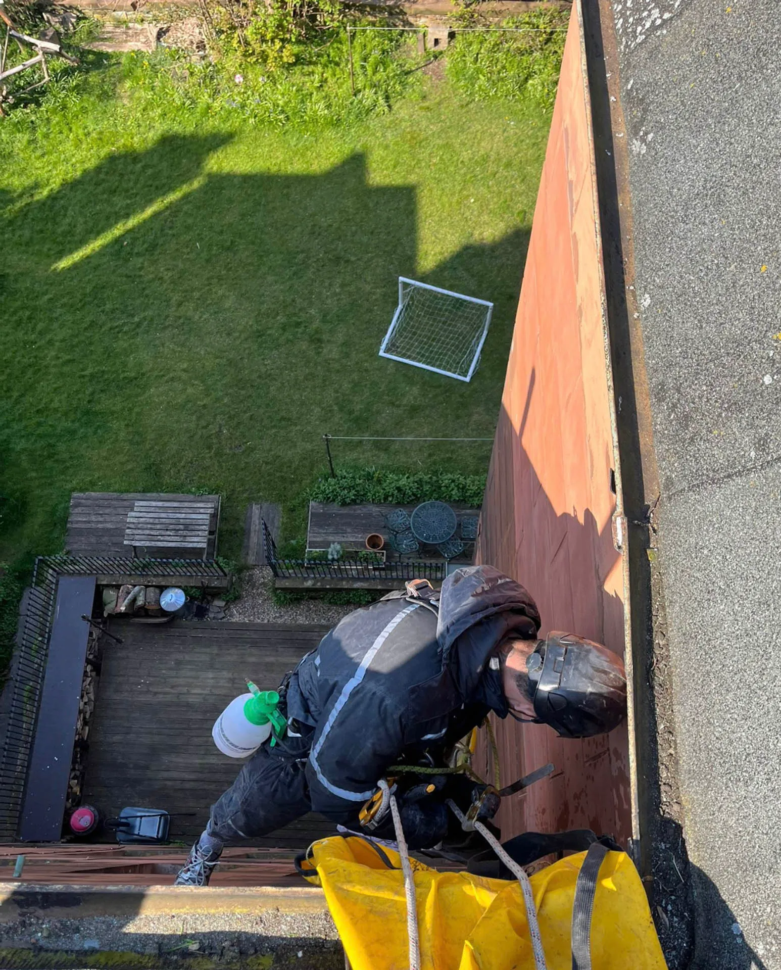 Rope access technician working on a roof, seen from above