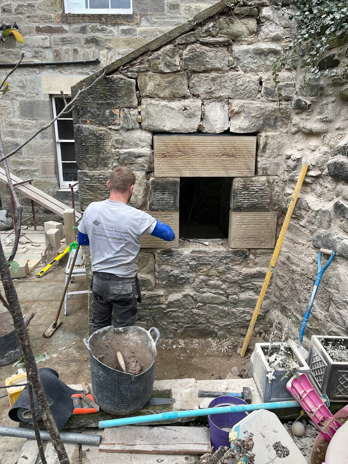 Stonemason rebuilding the stonework around an opening in a rubble wall