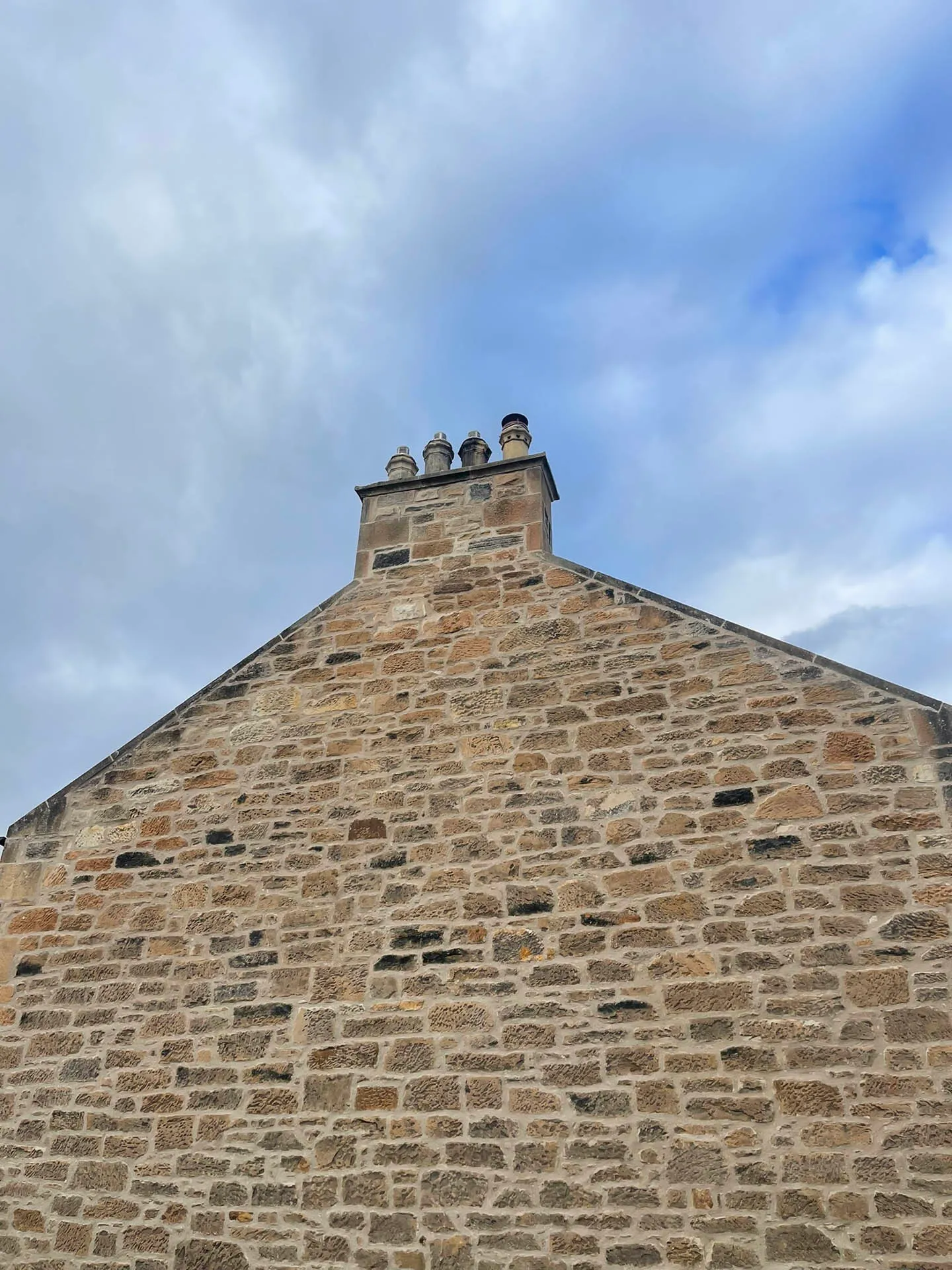Stone gable wall and chimney stack against a blue sky