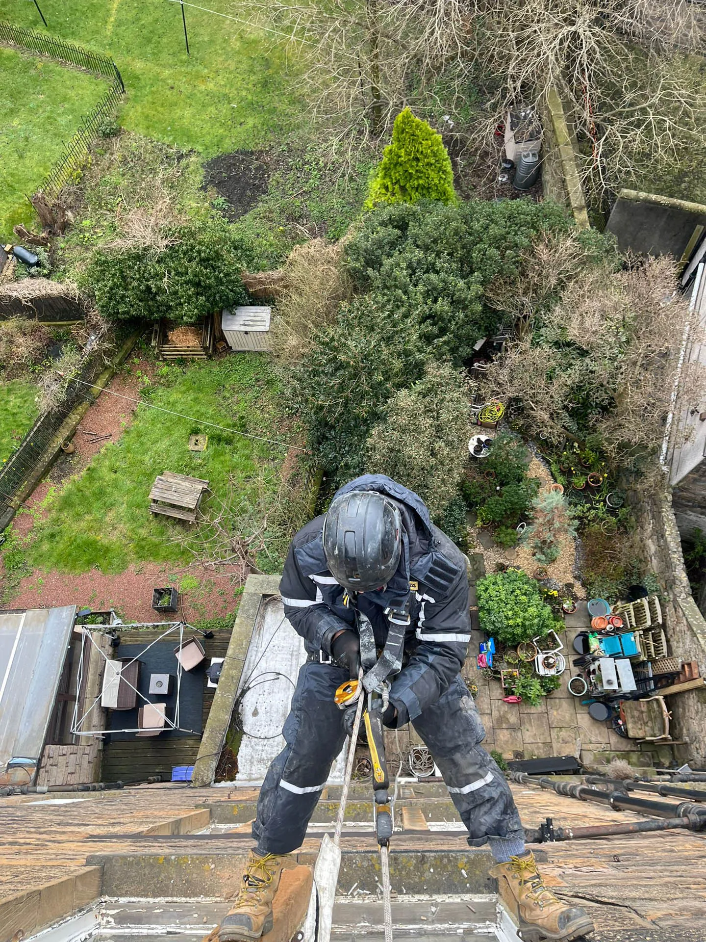 Rope access technician working over a roof edge in full harness
