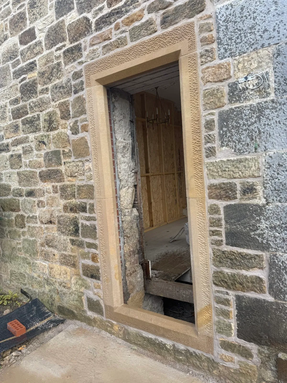 New door opening with tooled sandstone jambs, lintel and sill in a rubble stone wall