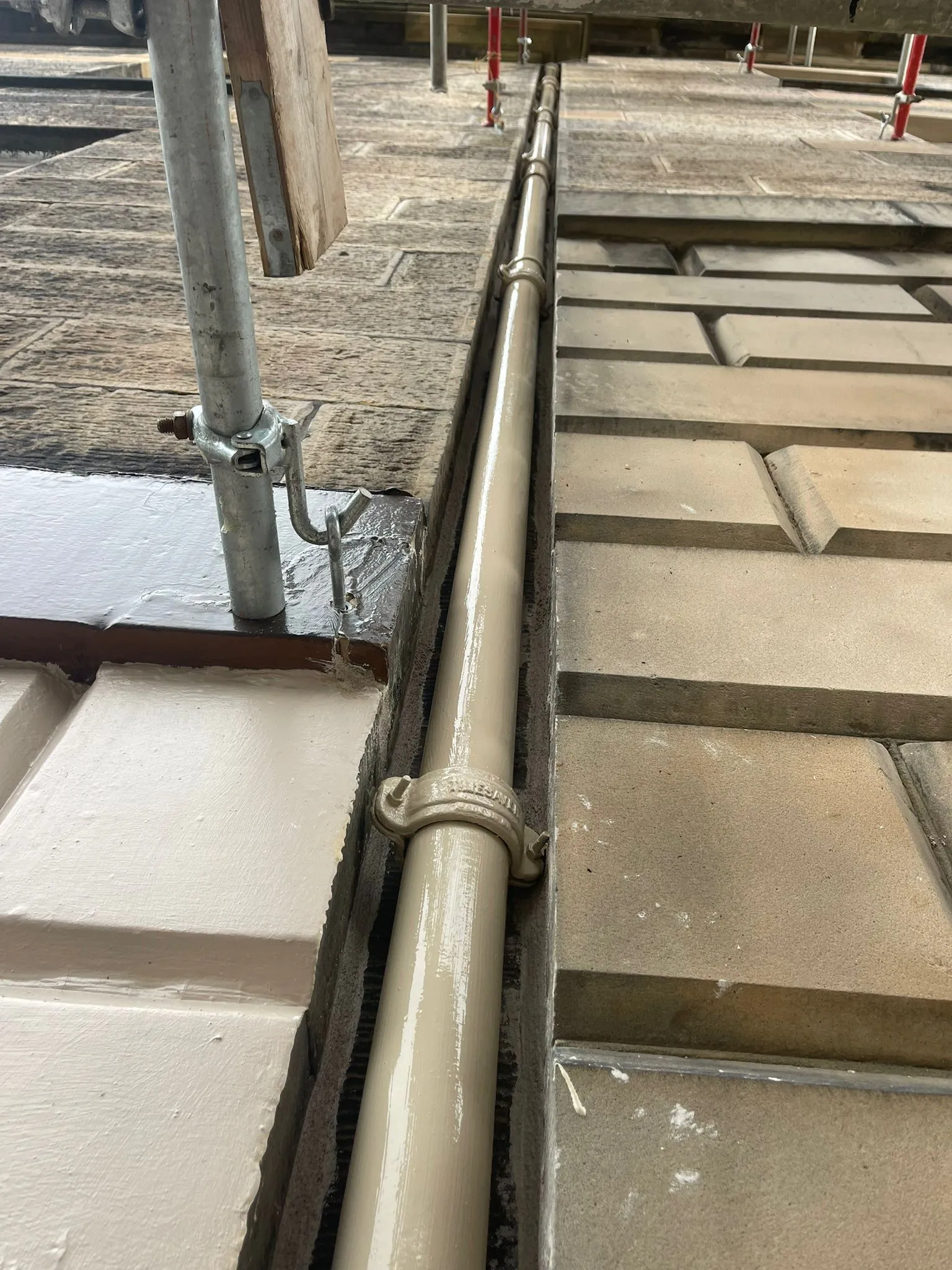 Cast iron rainwater pipe running along a parapet gutter
