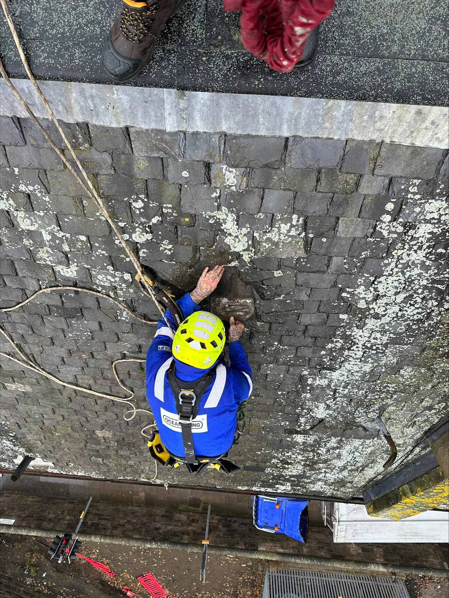 Rope access technician on a slated roof, viewed from above