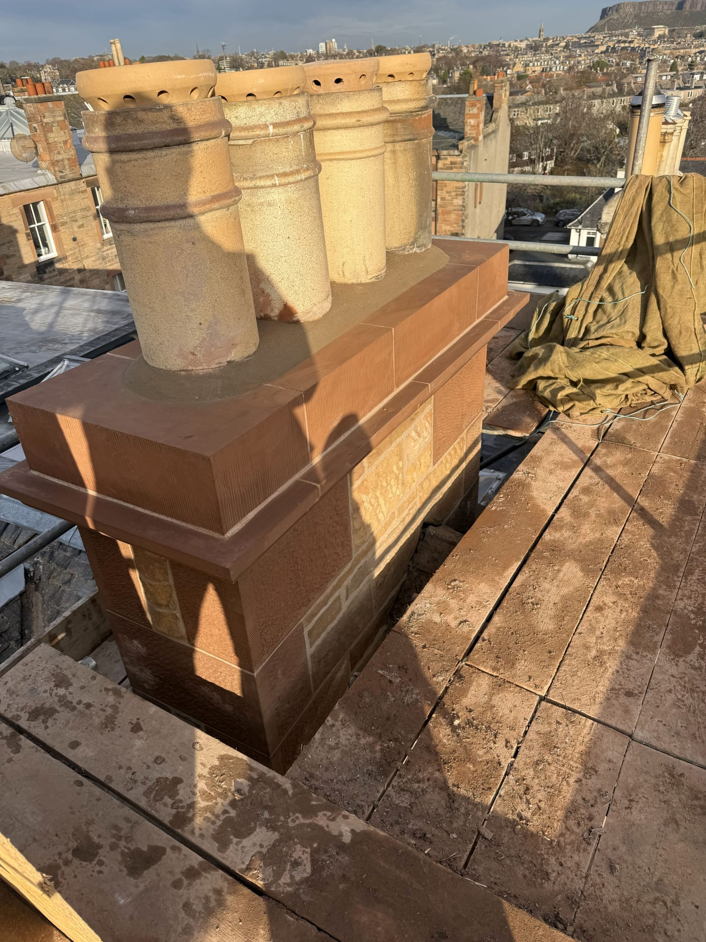 Rebuilt sandstone chimney head with a row of clay pots