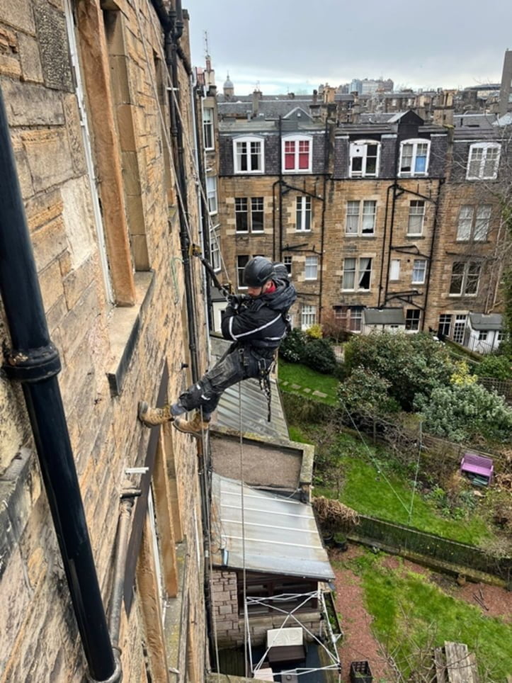 Rope access operative abseiling down the rear wall of a tenement