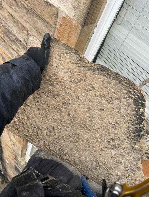 Operative kneeling on a large stone slab at roof level