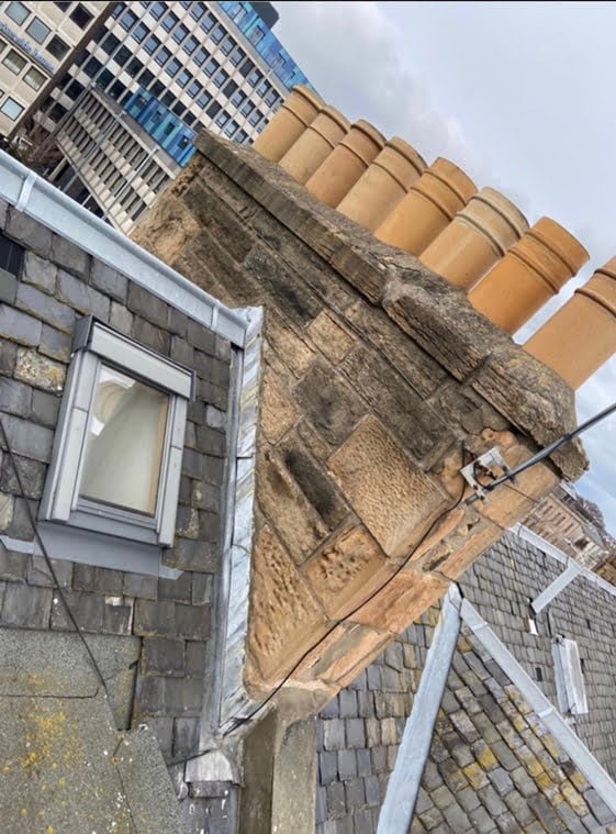 Clay chimney pots and stone skews at the edge of a slate roof