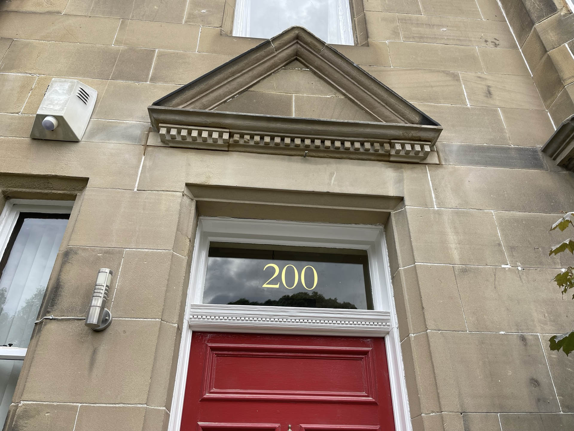 Stone doorway with a carved pediment and a red front door
